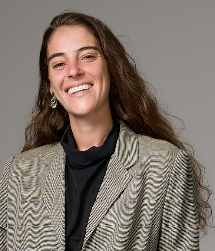 Portrait of Olivia Krok wearing black sweater and beige pattern blazer against grey background