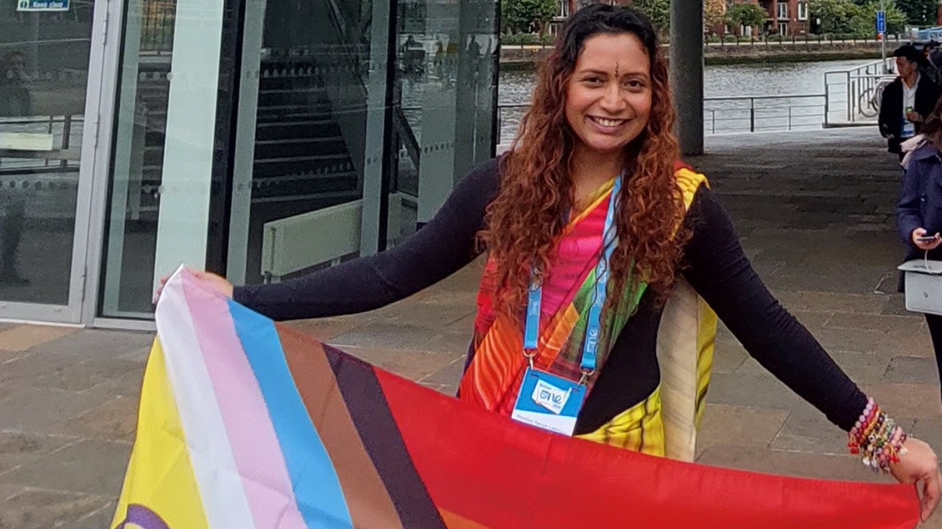 Nandini Tanya Lallmonis at the One Young World Summit Belfast 2023 holding a LGBTQIA+ flag