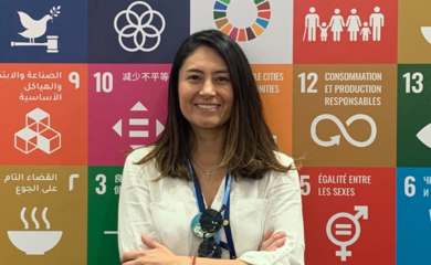 Picture of Alejandra Tellez smiling in front of a step and repeat showing the 17 Sustainable Development Goals